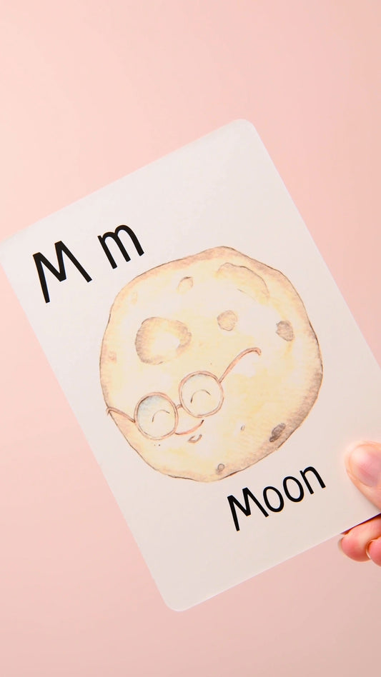 Parent holding the English Alphabet Card for M – Moon, showing a hand-painted watercolour illustration of a moon, perfect for early phonics learning.